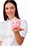 Confident businesswoman showing a piggybank against a white background