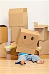 Little girl having fun in her new home unpacking playing with cardboard boxes