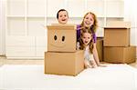 Happy kids and woman having fun in their new home playing among cardboard boxes