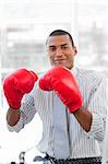 Successful businessman beating the competion with boxing gloves at his desk