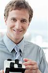 Smiling businessman holding a business card holder at work