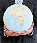 Close-up of a charismatic businessman holding a globe in the office