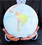 Close-up of a relaxed businessman holding a globe in the office