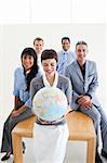 Positive international business people holding a terrestrial globe in the office