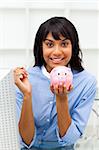 Smiling businesswoman saving money in a piggybank in the office