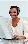 Afro-american businesswoman with headset on working at a computer in a call-center