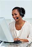 Cheerful businesswoman with headset on working at a computer in a call-center