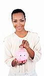 Charming businesswoman saving money in a piggybank against a white background