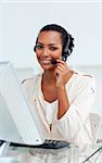 Charming businesswoman with headset on working at a computer