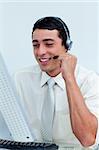 Young businessman using headset working at a computer