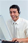 Cheerful businessman using headset working at a computer