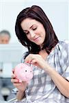 Glowing businesswoman saving money in a piggy-bank at her desk