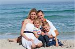 Portrait of a cheerful family sitting on the sand at the beach