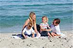 Caring parents with their children sitting on the sand at the beach