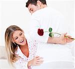 Cheerful woman finding a rose against a white background