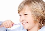 Cute boy brushing his teeth against a white background