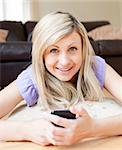 Delighted woman sending a text lying on a bed at home