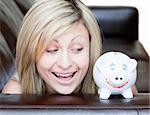 Happy woman using a piggybank against a white background