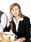 Worried businesswoman talking on phone while having breakfast at home