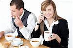 Smiling businesswoman talking on phone while having breakfast with her husband at home