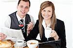 Young couple of business people reading a newspaper while having breakfast at home