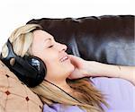 Smiling woman using headphones on a sofa