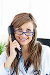 Smiling female doctor talking on the phone in her office