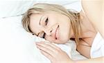 Smiling woman relaxing in a bed at home
