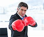 Furious businessman wearing boxing gloves in his office