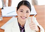 Confident businesswoman with thumbs up at work