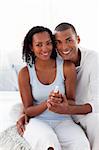 Smiling Afro-american couple finding out results of a pregnancy test in the bedroom