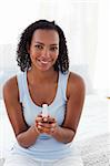 Smiling woman finding out results of a pregnancy test sitting on a bed