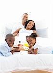 Merry family having breakfast in the bedroom at home