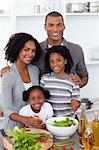 Ethnic family preparing salad together in the kitchen