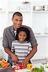 Smiling father helping his son cut vegetables in the kitchen