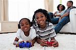 Happy siblings playing video game lying on the floor
