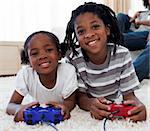 Close-up of siblings playing video game lying on the floor