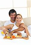 Romantic couple having breakfast lying in the bed at home