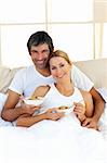 Blond woman and her boyfriend eating cereals lying in the bed