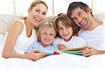 Smiling family reading a book  lying in bed