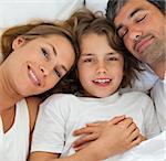 Close-up of parents hugging their son lying in the bed