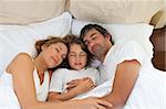 Cute child and his parents sleeping together in the bedroom