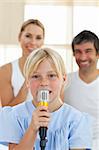 Adorable little girl singing with a microphone sitting on her parent's bed