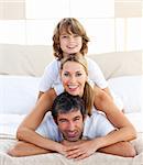 Little boy and his parents playing lying on the bed