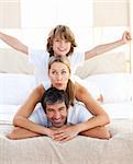 Cute child and his parents having fun lying on the bed