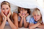 Attractive mother having fun with her children on bed at home