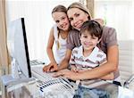 Caring mother and her children at a computer in the living-room