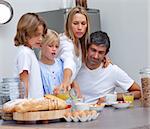 Smiling parents helping children baking cookies in the kitchen