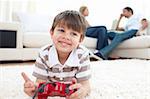 Smiling little boy playing video games lying on the floor