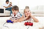 Adorable siblings playing video games lying on the floor